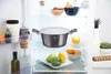 A pot with a lid is placed on a shelf in an open refrigerator, surrounded by various food items and containers. Voir les images du produit