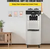 A commercial soft ice cream maker is displayed in a clean, modern setting, with decorative pictures of ice cream cones on the wall and a wooden cabinet with a plant on the left. Náhľad obrázku produktu