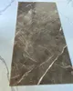 A single rectangular tile with a gray marble pattern is laid on a white and light gray surface. Produktbild-Vorschau