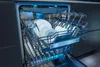 An open dishwasher filled with clean dishes and glassware, illuminated by blue interior lights. Produktbild-Vorschau