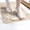 Feet with soap suds standing on a textured beige bath mat. Voir les images du produit