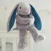 A plush bunny toy is sitting on the edge of a white crib. Produktbild-Vorschau