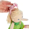 A close-up of a doll's head with a hand adjusting a flower headband. Voir les images du produit