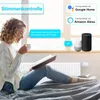 A woman is sitting on a bed, reading a book and drinking from a mug, with smart home devices and a radiator thermostat visible. Podgląd zdjęcia produktu