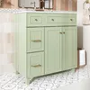 A light green bathroom vanity with gold hardware sits on a patterned floor, with a tiled wall and mirror in the background. Anteprima dell’immagine prodotto