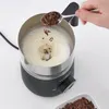 A hand adding chocolate shavings to a milk frother. Produktbild-Vorschau