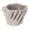 A planter shaped like a face with hands covering it, shown from a diagonal angle. Náhled obrázku produktu