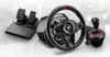 A racing wheel, pedals, and gear shifter are displayed against a blurred background of cars and a road. Anteprima dell’immagine prodotto