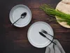 A table setting with two plates, cutlery, and a bunch of grass on a wooden table. Náhľad obrázku produktu