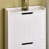 A close-up view of a white shoe cabinet with fluted doors and black handles. Produktbild-Vorschau