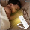 A baby sleeping in bed with a small LED reading light illuminating the scene. Náhľad obrázku produktu