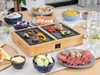 A table set for a meal with a grill, various food items, and drinks. Produktbild-Vorschau