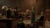 A group of students in a dimly lit room, possibly a classroom or study hall, gathered around a teacher. Produktbild-Vorschau