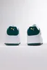 A pair of white Puma sneakers with green and gold accents, shown from the back. Produktbild-Vorschau