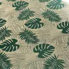 A close-up view of a tablecloth with a monstera leaf pattern. Produktbild-Vorschau