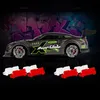 A remote-controlled drift car with racing decals is shown in the foreground, with a graffiti-covered wall in the background. Several red and white traffic barriers are placed in front of the car. Produktbild-Vorschau