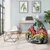 A brightly colored bean bag chair with graffiti-style art sits in a modern room next to a desk and a large window. Voir les images du produit