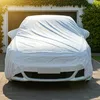 A white car covered with a white tarp parked in front of a garage. Produktbild-Vorschau