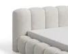A close-up view of a beige upholstered bed frame with a mattress. Voir les images du produit