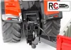 Close-up view of the rear hitch mechanism of a red toy tractor, showing a trailer attachment point and a remote control plug icon. Produktbild-Vorschau