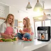 A mother and daughter are in a kitchen, preparing food. The daughter is sitting on a counter, while the mother is chopping vegetables. An air fryer is visible on the counter. Produktbild-Vorschau