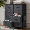 A dark gray fabric chest of drawers with eight drawers, some of which are open, revealing toys and balls. The top of the chest holds two containers of baby formula and folded towels. A plant is visible on the left. Voir les images du produit