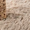 A close-up view of a shaggy rug with a woven basket edge. Anteprima dell’immagine prodotto