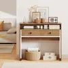 A desk with drawers and shelves is set up in a room with a couch and rug. Produktbild-Vorschau