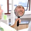 A person is holding a hand mirror in a dental office. Produktbild-Vorschau