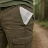 A close-up shot of a person's pocket with a handkerchief peeking out, set against a blurred forest background. Produktbild-Vorschau