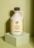 A bottle of maple syrup is placed on a light green cube against a light green background. Produktbild-Vorschau