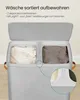 A close-up view of a gray fabric laundry basket with two compartments, one filled with a light-colored blanket and the other with a dark-colored garment. A magnified inset shows markings for 'Light' and 'Dark'. Produktbild-Vorschau