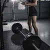 A person is preparing to lift weights in a home gym. Produktbild-Vorschau