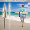 A person walking on a beach carrying a folded umbrella in a bag. Produktbild-Vorschau