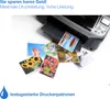 A printer is shown with several printed photos scattered around it. Produktbild-Vorschau