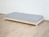 A children's wooden single bed with a gray mattress is shown against a white wall and on a wooden floor. Produktbild-Vorschau