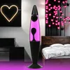A pink lava lamp is shown in a bedroom setting, next to a bed and a heart-shaped neon light. Produktbild-Vorschau
