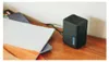 A black GoPro dual battery charger sits on a wooden surface next to a stack of books. Anteprima dell’immagine prodotto