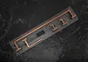 A set of copper-colored bathroom hooks arranged on a dark, textured surface. Anteprima dell’immagine prodotto