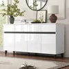 A white high-gloss sideboard with black accents is shown in a well-lit room, with decorative items on top and a rug in the foreground. Produktbild-Vorschau