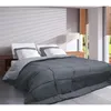 A bed with a gray comforter and white pillows in a room with blinds and a window. Voir les images du produit