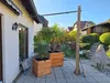 A backyard patio with two wooden planters, a palm tree, and a small wooden shed. Produktbild-Vorschau