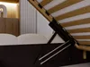 A close-up view of the underside of a bed frame, showing the lifting mechanism and wooden slats. Produktbild-Vorschau