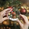 Hands holding a clear Christmas ornament with a clay reindeer inside, in front of a decorated Christmas tree. Produktbild-Vorschau