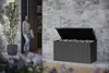 A woman is standing in a doorway next to a large outdoor storage box filled with cushions. Produktbild-Vorschau