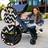 A woman is interacting with a baby in a stroller outdoors. Náhled obrázku produktu
