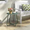 A green metal side table with a flower arrangement and a cup of coffee on a patio next to a white bench with cushions. Produktbild-Vorschau