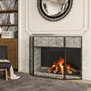 A fireplace with a fire burning, protected by a three-panel screen, in a living room setting with a chair and bookshelf. Podgląd zdjęcia produktu