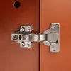 A close-up view of a metal hinge attached to a brown wooden surface. Anteprima dell’immagine prodotto