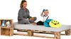 A woman and a child are sitting on a bed made of wooden pallets. There are stuffed animals in wooden crates next to the bed. Produktbild-Vorschau